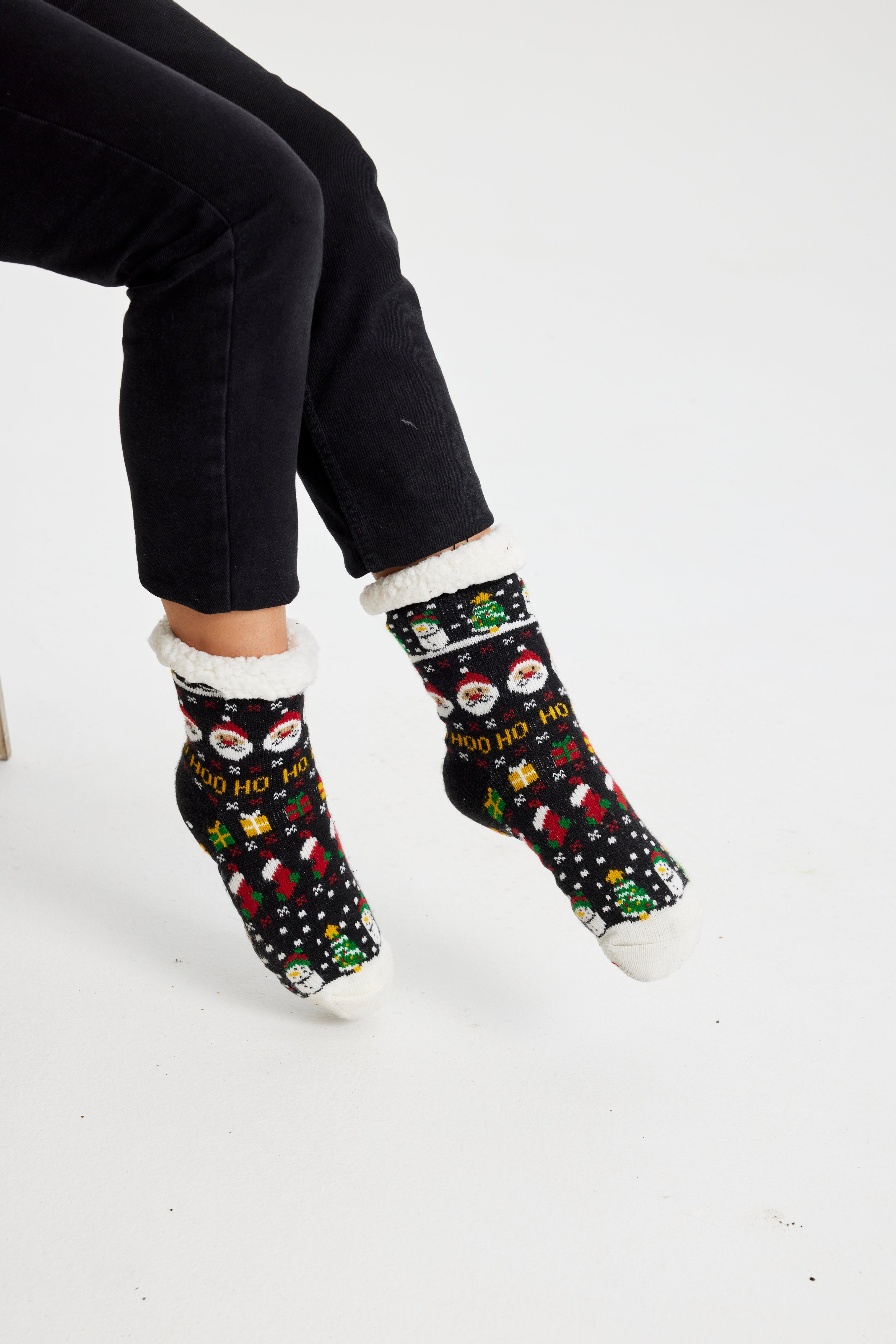 Une paire de pieds portant des chaussettes de Noël noires avec un motif de Noël.